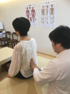 座った状態で背中に手を添えて身体を確認する様子